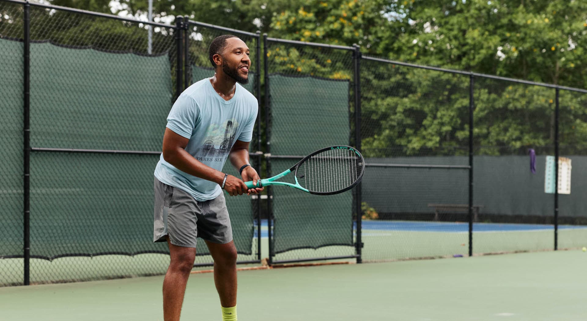 A man with a tennis racket stands ready to receive the next serve. (Photo Credit: Erin Sintos)