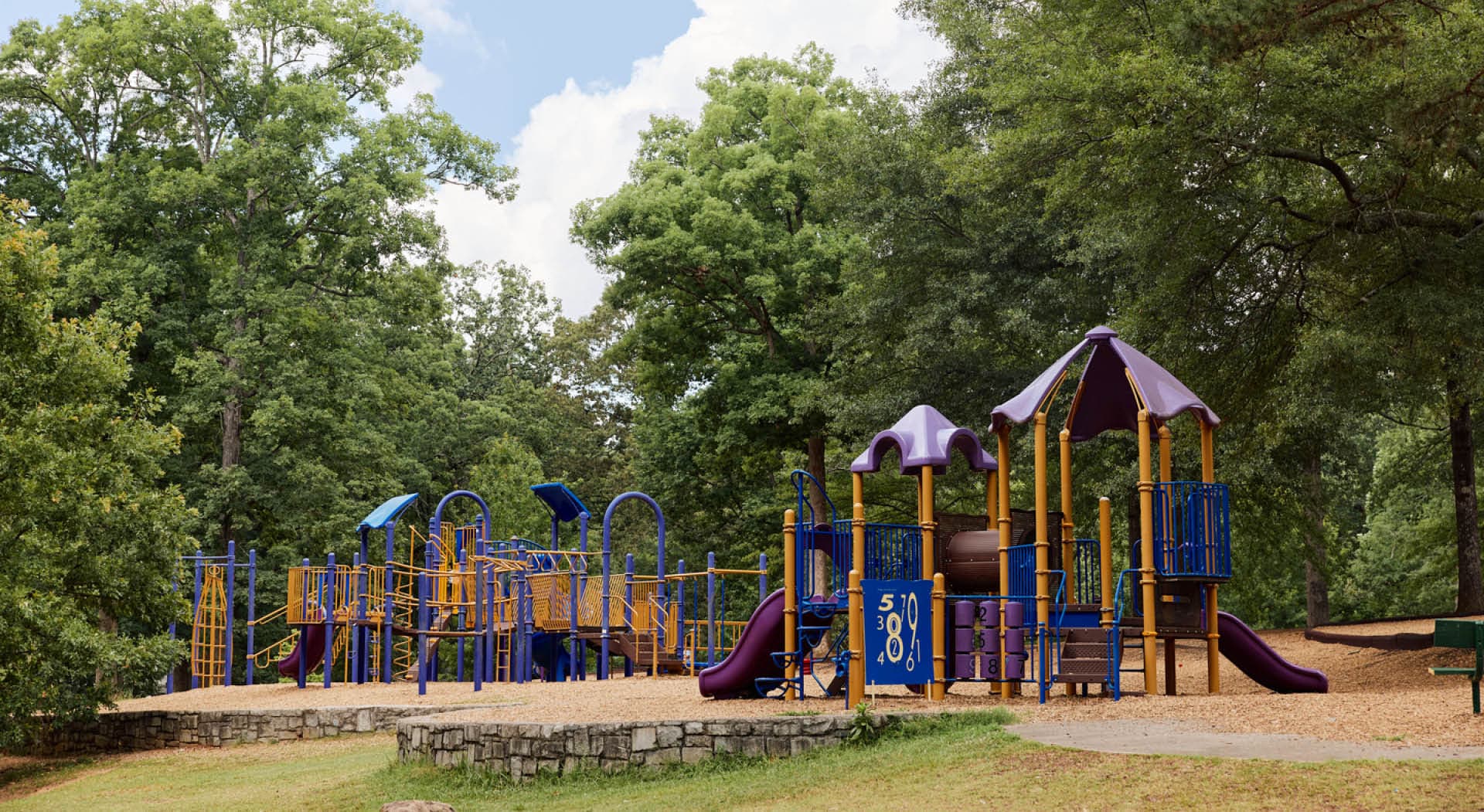 A few large playground structures amongst large trees in Perkerson Park. (Photo Credit: Erin Sintos)