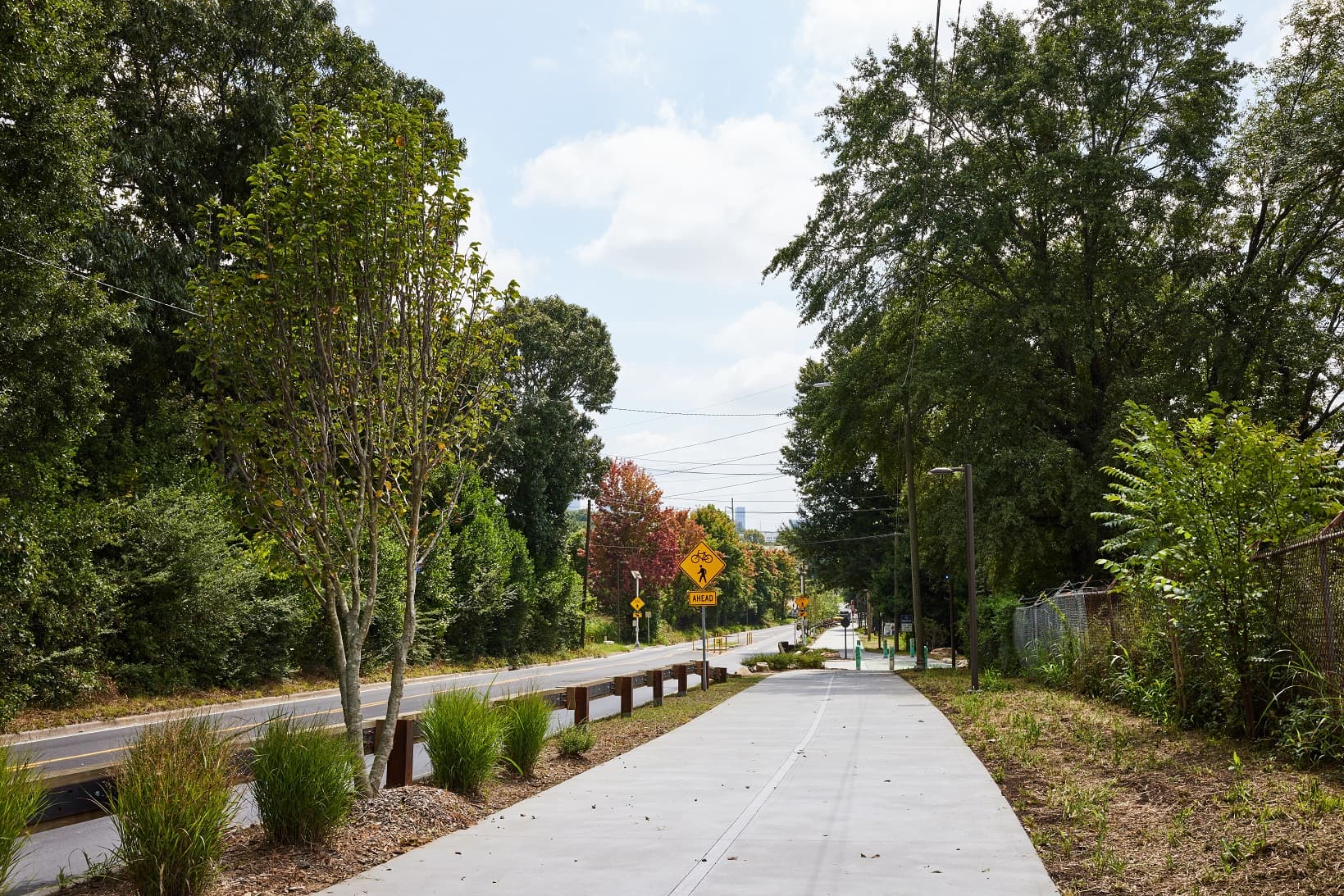 A wide path with landscaping runs alongside a road.