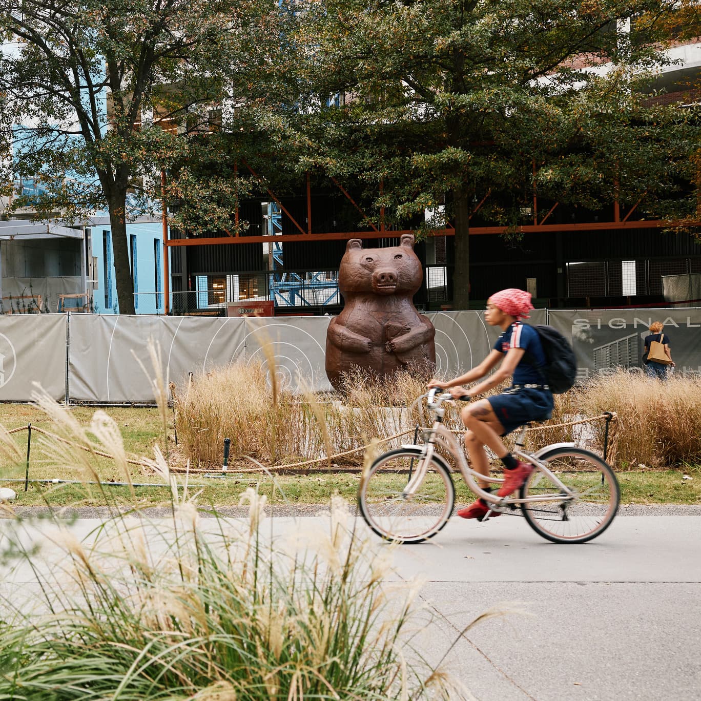 A person rides a bike past a large bear sculpture along the Atlanta Beltline.